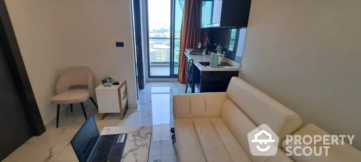 Modern living room with elegant cream sofa, marble flooring, and access to a sunlit balcony with a view, perfect for urban living.