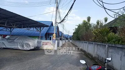 Quiet residential street with covered parking and blue-roofed houses.