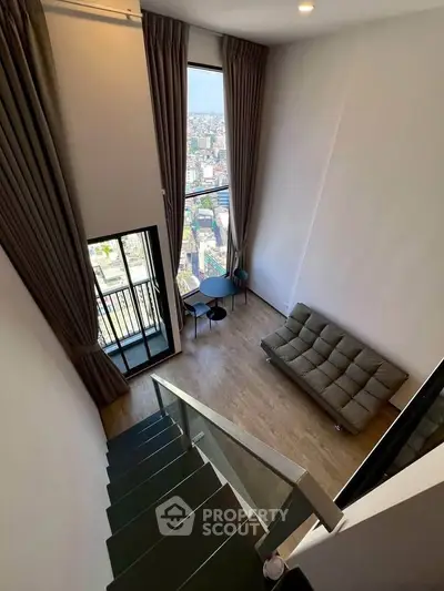 Stunning loft apartment with high ceilings and city view, featuring modern furniture and floor-to-ceiling windows.