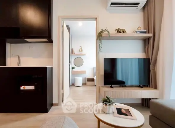 Modern living room with open kitchen, stylish decor, and natural light.