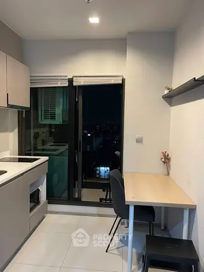 Modern compact kitchen with sleek design and balcony view in urban apartment.