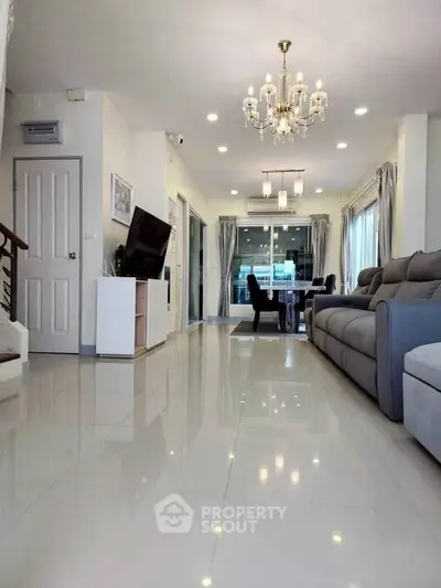 Spacious living room with elegant chandelier and modern furnishings in a bright, open layout.
