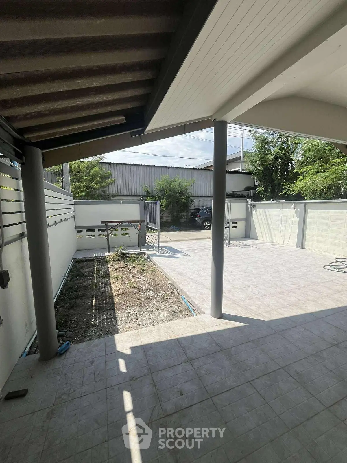 Spacious outdoor patio with tiled flooring and partial garden view