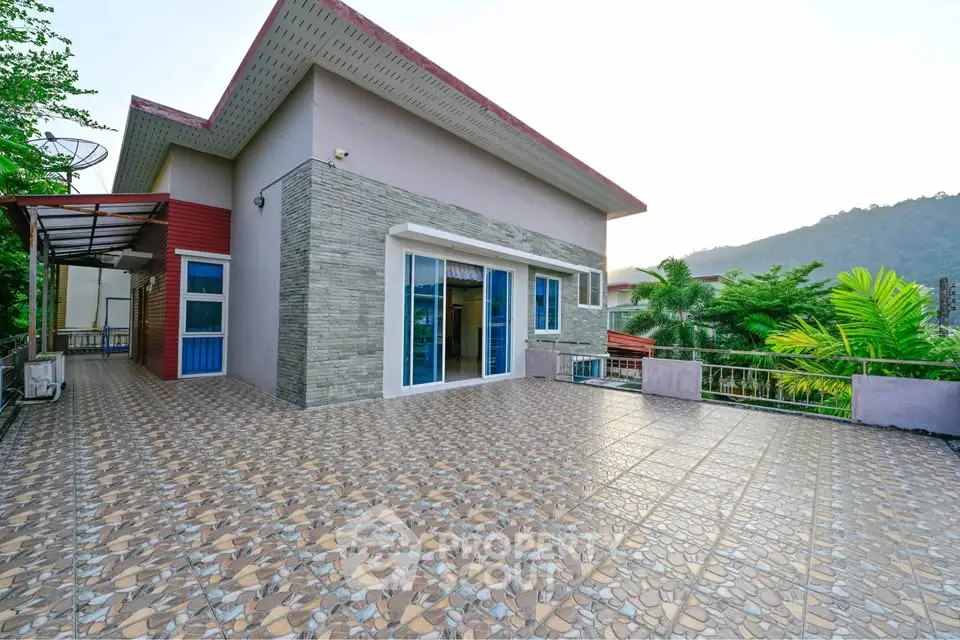 Spacious modern house with large tiled patio and scenic mountain view.