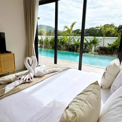 Luxurious bedroom with pool view, featuring elegant decor and large glass doors opening to a serene outdoor pool.