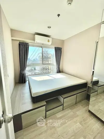 Modern bedroom with large window and city view, featuring built-in storage and air conditioning.