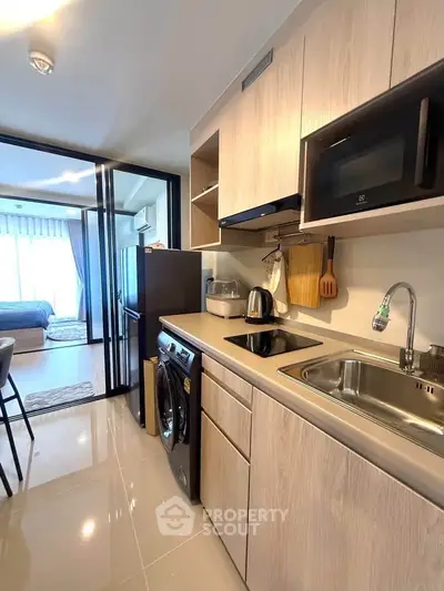 Modern kitchen with sleek appliances and open layout leading to a cozy bedroom.