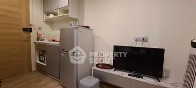 Compact modern kitchen with fridge and TV in cozy apartment