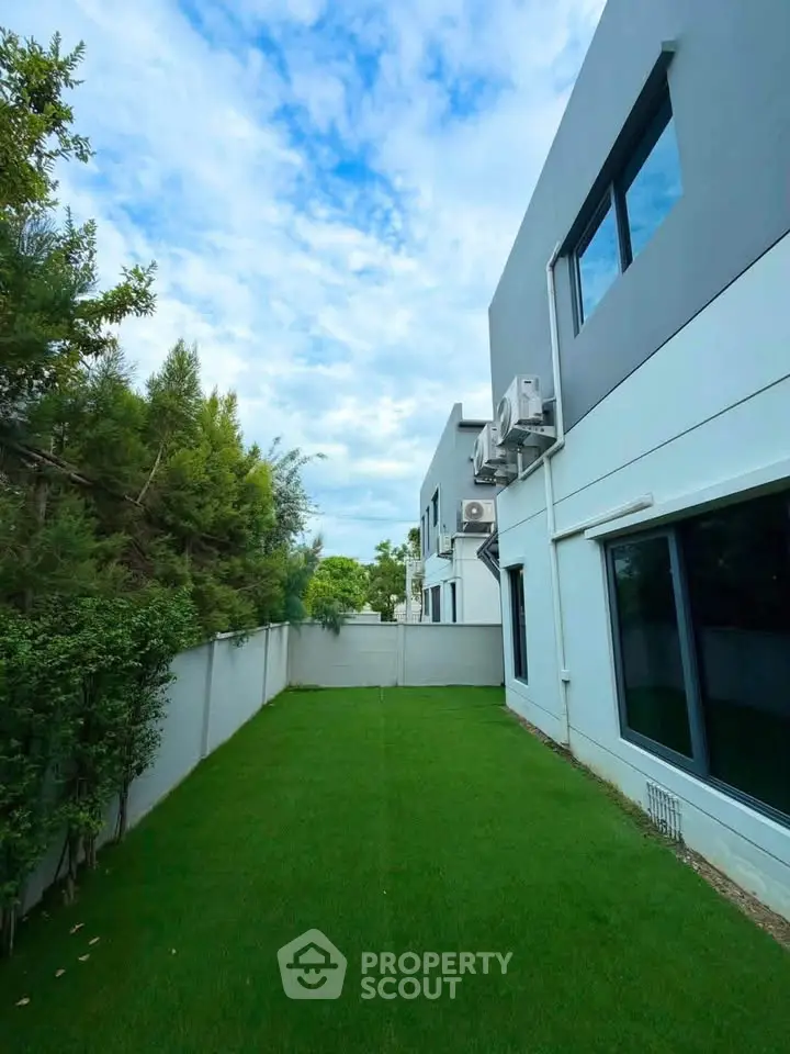 Modern townhouse with lush green backyard and sleek exterior design