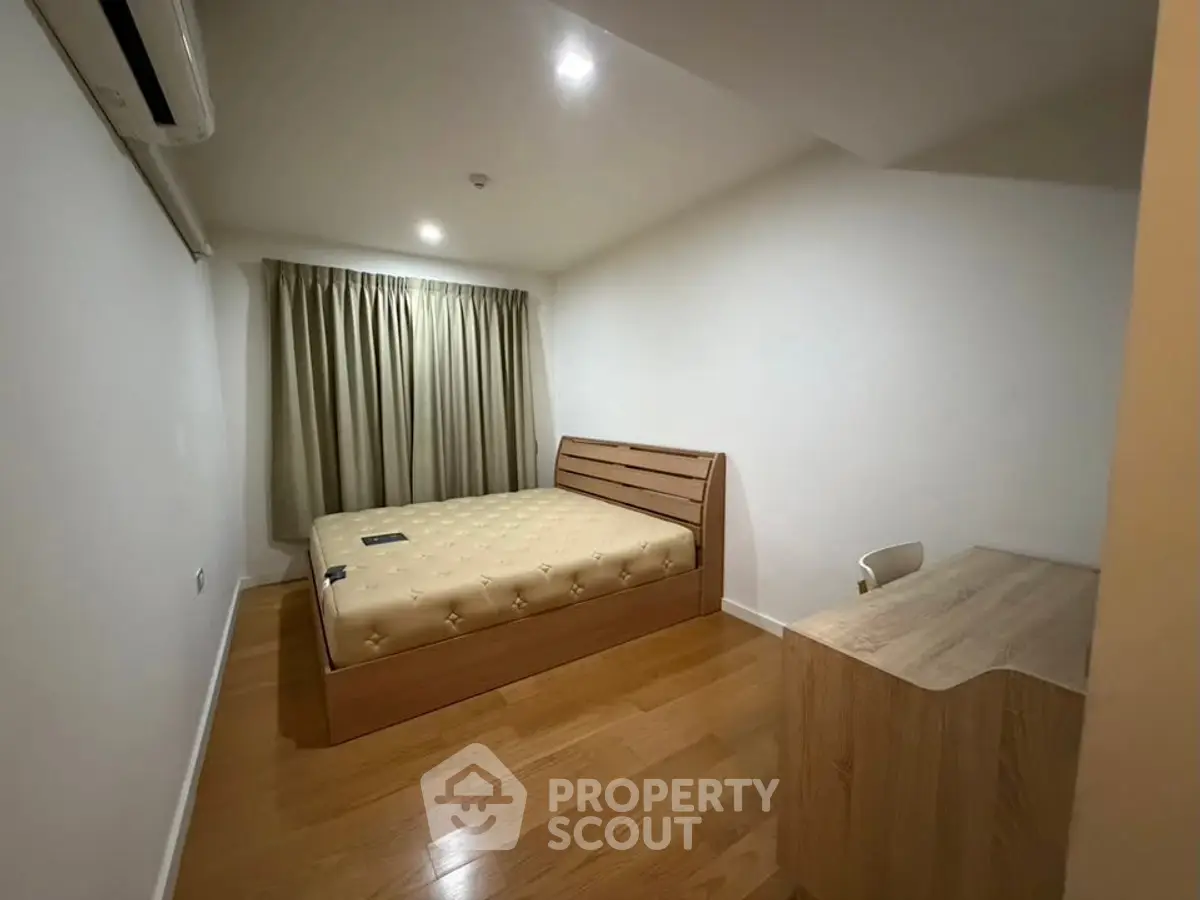 Cozy bedroom with wooden flooring and modern furnishings in a minimalist style.