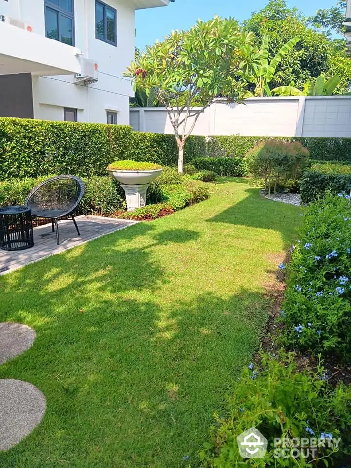 Charming garden with lush greenery and cozy seating area in modern residential property.