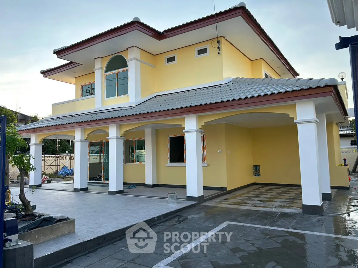 Stunning two-story yellow house with spacious driveway and elegant columns.