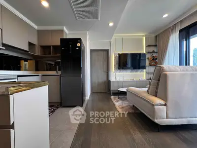 Modern living room with sleek kitchen, stylish decor, and large windows offering natural light.
