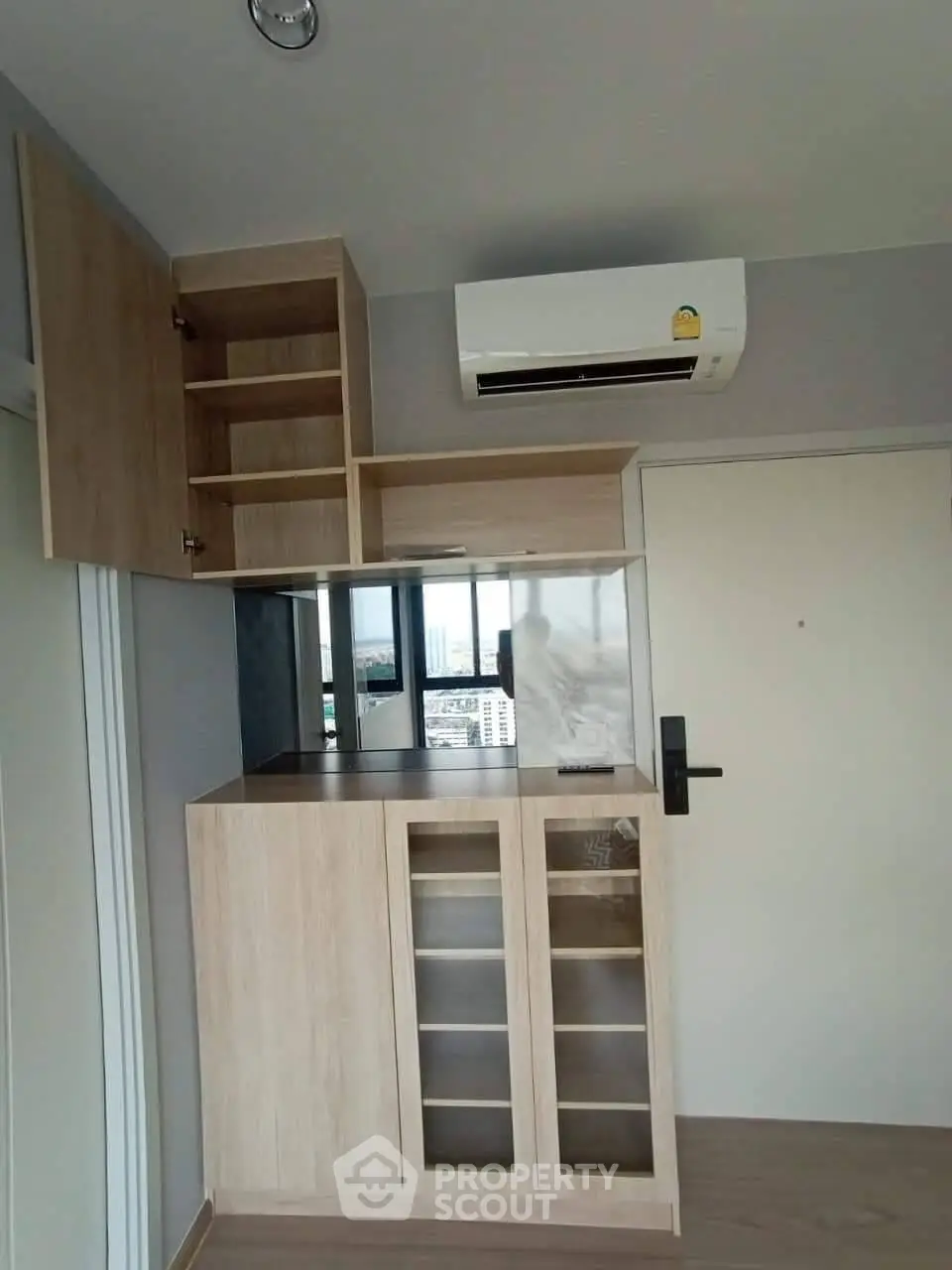 Modern apartment interior with built-in wooden storage and air conditioning unit.