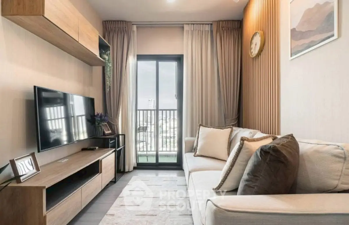 Modern living room with cozy sofa and large TV, featuring elegant decor and natural light.