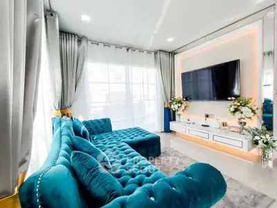 Luxurious living room with plush teal sofa and large TV, perfect for relaxation.