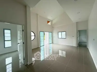 Spacious modern living room with high ceilings and large windows in a bright, open layout.
