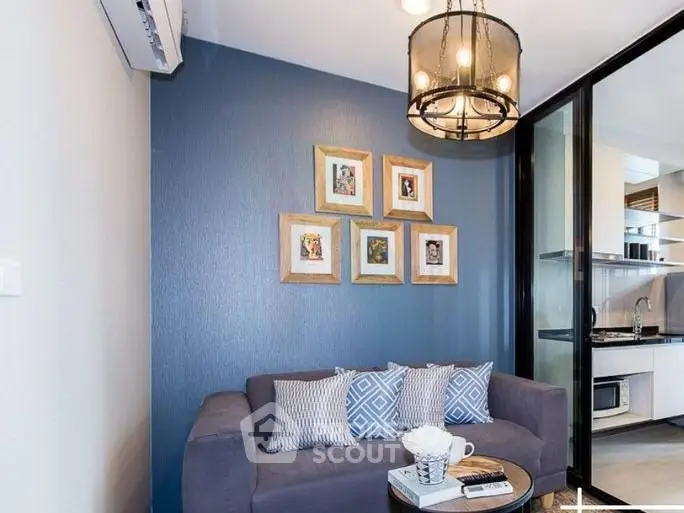 Modern living room with stylish decor and open kitchen layout, featuring a cozy sofa and elegant lighting.
