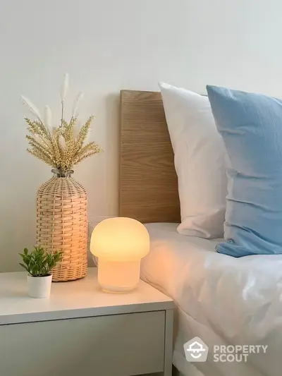 Cozy bedroom corner with stylish lamp and decorative vase on bedside table.