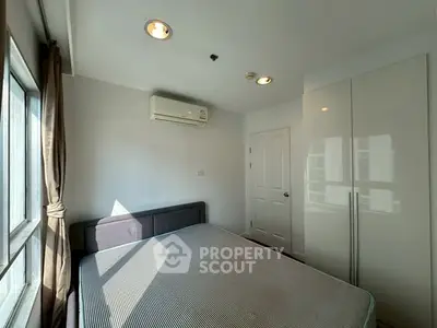 Bright bedroom with large window and modern air conditioning unit.