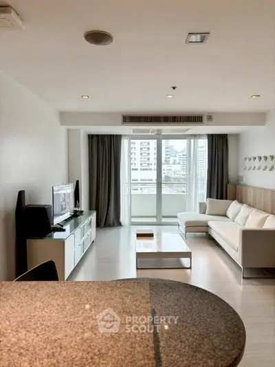 Modern living room with large windows and city view, featuring sleek furniture and neutral tones.