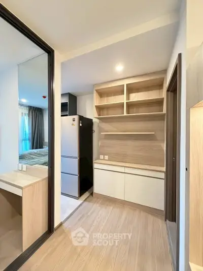 Modern kitchen with sleek cabinetry and stainless steel fridge in open layout apartment.
