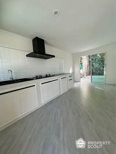 Modern kitchen with sleek design and gas stove, featuring large sliding doors opening to a stone wall view.