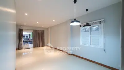Spacious living room with modern lighting and large window in a bright, open space.