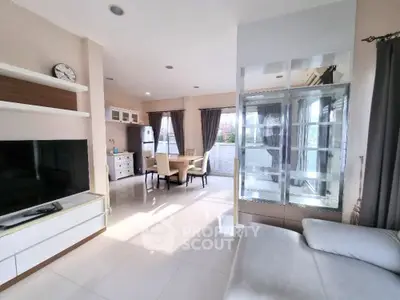 Spacious modern living room with open kitchen and dining area, featuring sleek furniture and natural light.