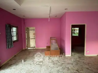 Spacious room with vibrant pink walls and marble flooring, featuring large windows for natural light.