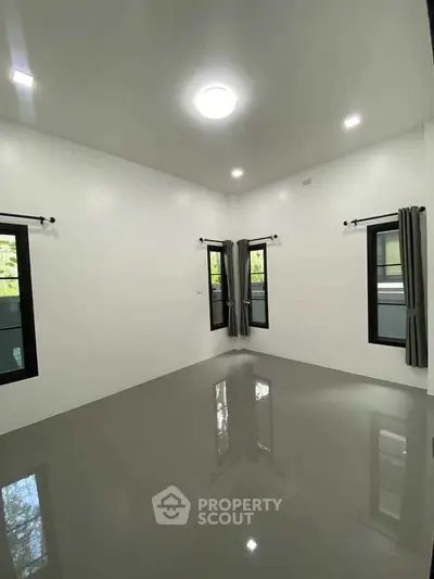 Spacious empty room with glossy floor and large windows, perfect for customization.