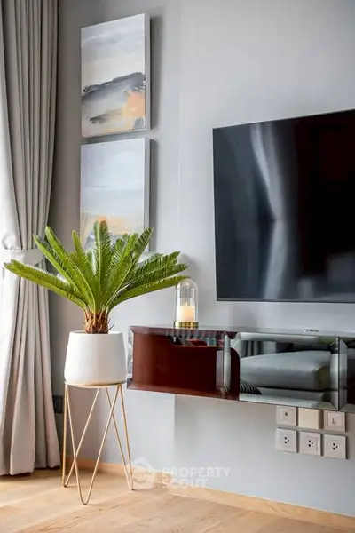 Modern living room with stylish decor, featuring a large TV, elegant plant, and contemporary artwork.