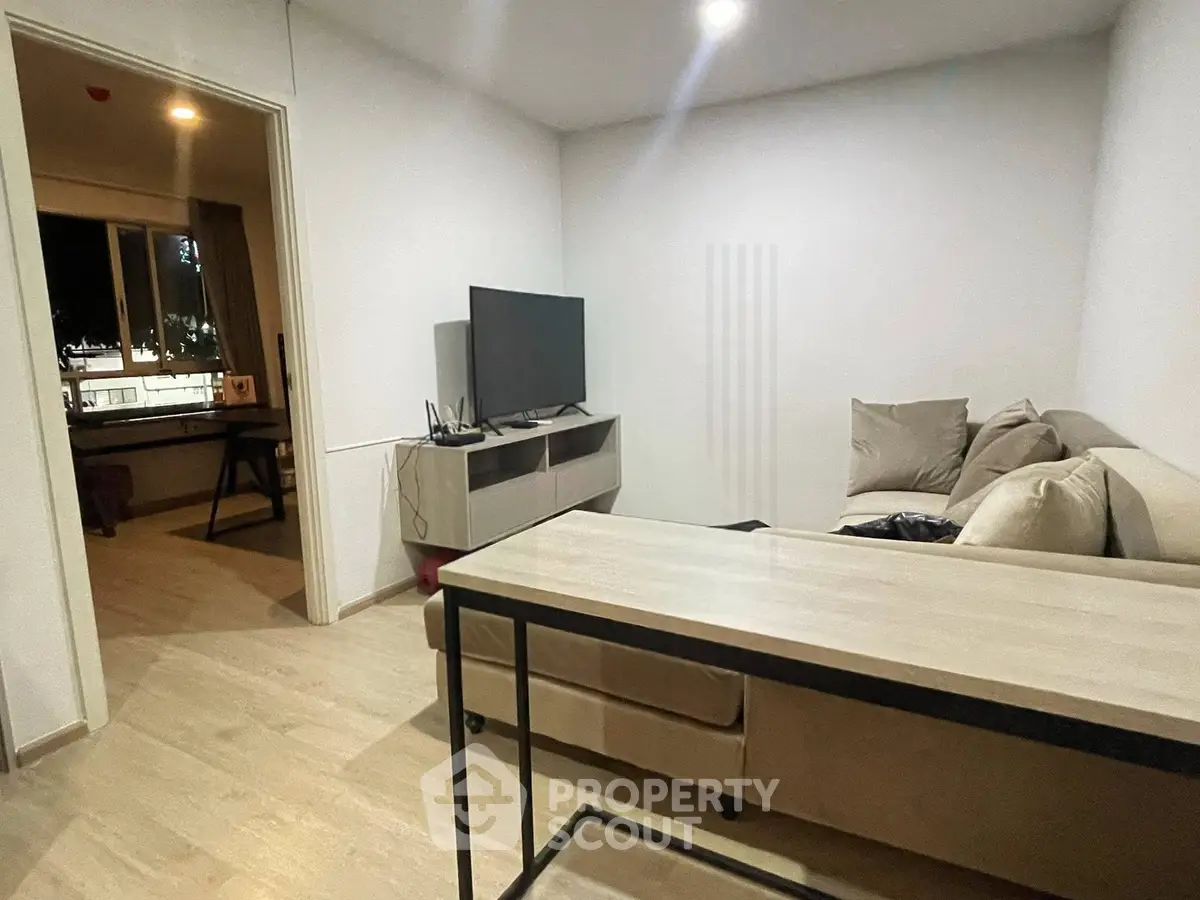 Modern living room with cozy sofa and flat-screen TV, open layout to dining area, perfect for relaxation.