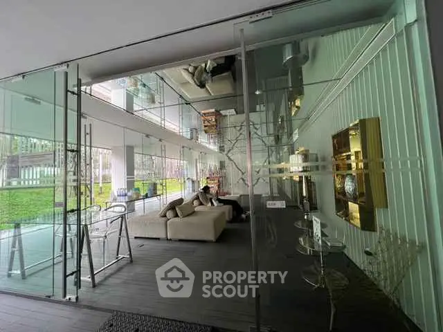 Modern glass-walled living room with stylish decor and lush garden view.