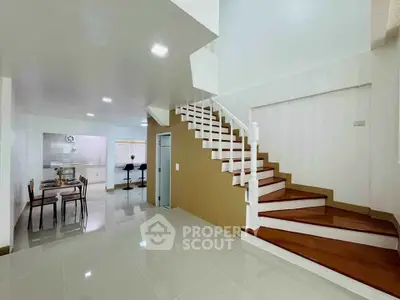 Modern open-plan living area with elegant staircase and dining space