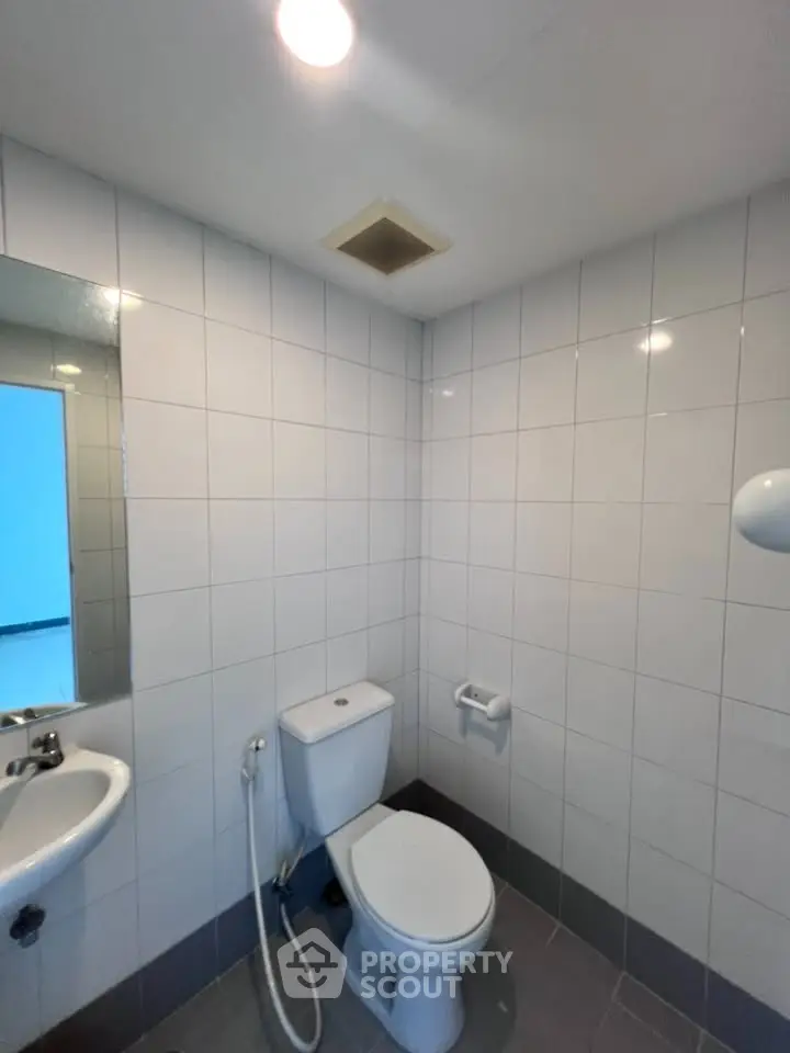 Compact bathroom with white tiles and modern fixtures, ideal for small spaces.