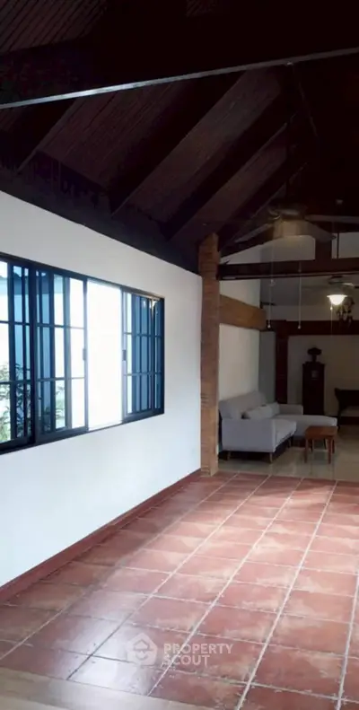Charming living room with high wooden ceiling and tiled floor, featuring cozy seating area.