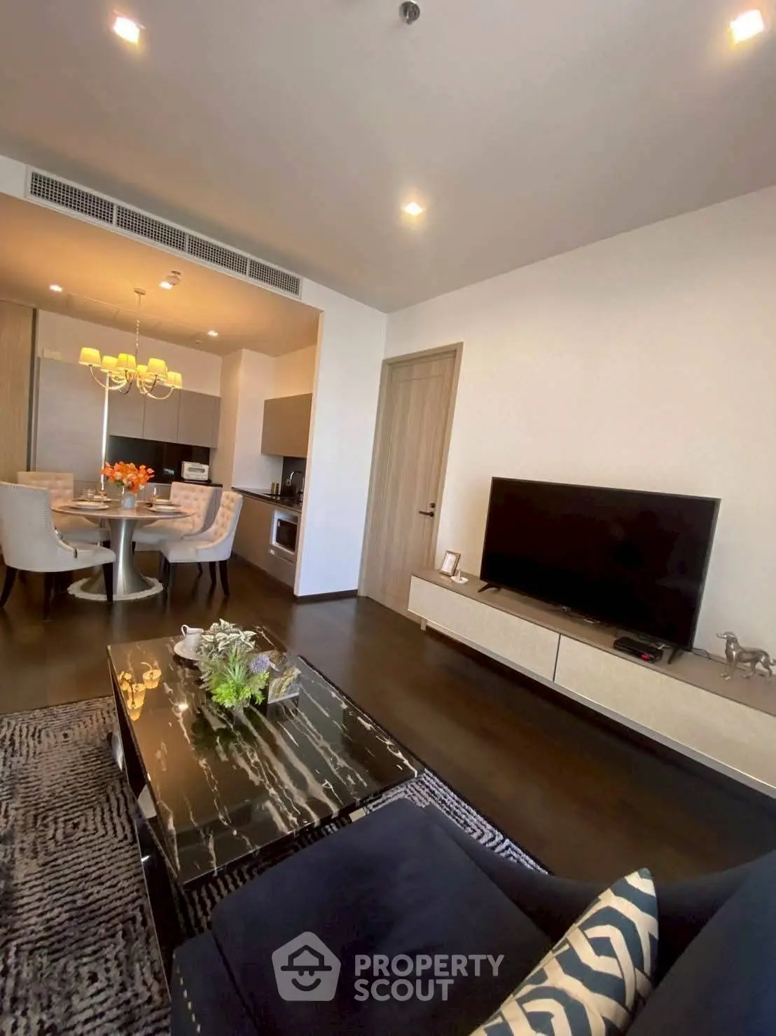 Modern living room with open kitchen, stylish decor, and dining area in a contemporary apartment.