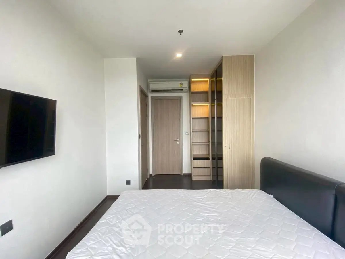 Modern bedroom with sleek design, featuring a wall-mounted TV and built-in wardrobe.