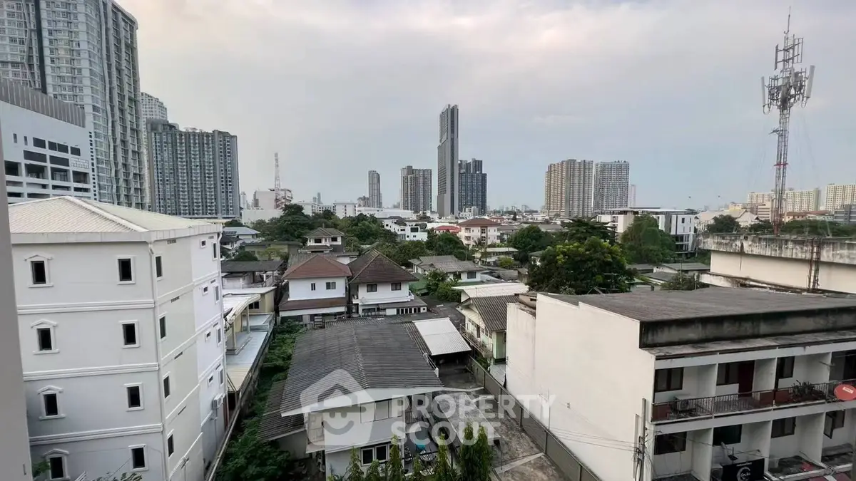 Stunning urban skyline view from a high-rise apartment, showcasing modern city living with lush greenery and tall buildings.