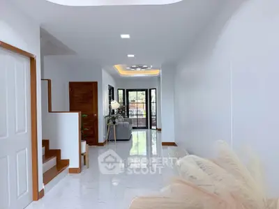 Spacious modern living room with elegant staircase and bright natural lighting.