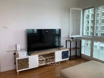 Modern living room with sleek TV setup and large windows offering natural light.