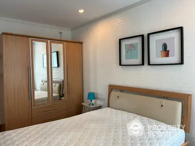 Cozy bedroom with a comfortable queen-size bed, wooden wardrobe, and chic wall art, perfect for restful nights in a modern home.