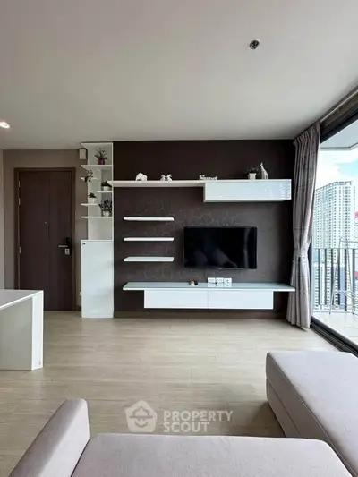 Modern living room with sleek TV unit and large balcony offering city views.
