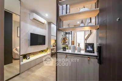 Modern living room with stylish decor and built-in shelving, featuring a wall-mounted TV and elegant lighting.