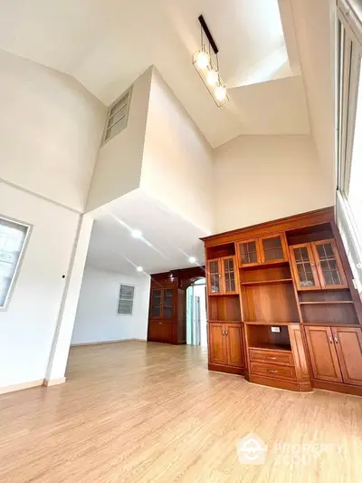 Spacious living room with high ceiling and elegant wooden cabinetry