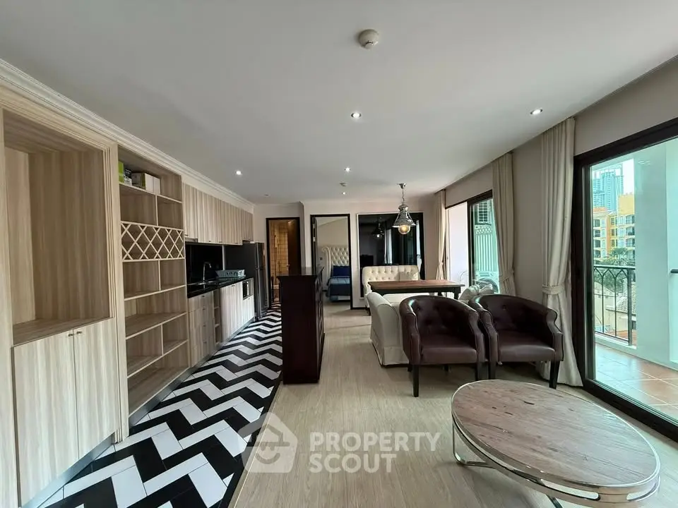 Spacious living room with modern open kitchen and large windows offering city views.