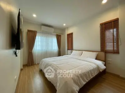 Spacious bedroom with cozy lighting and modern decor, featuring a large bed and elegant window treatments.