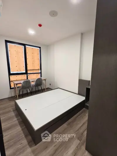 Modern minimalist bedroom with sleek furniture and large window, perfect for urban living.