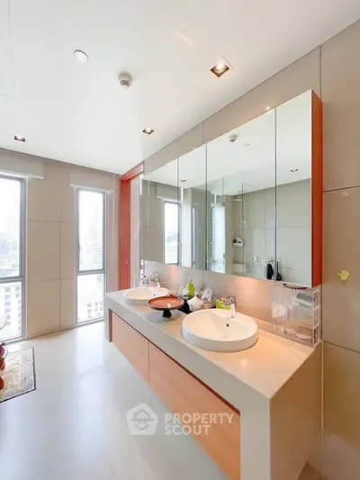 Spacious modern bathroom with dual sinks and large mirrors in a luxury apartment.